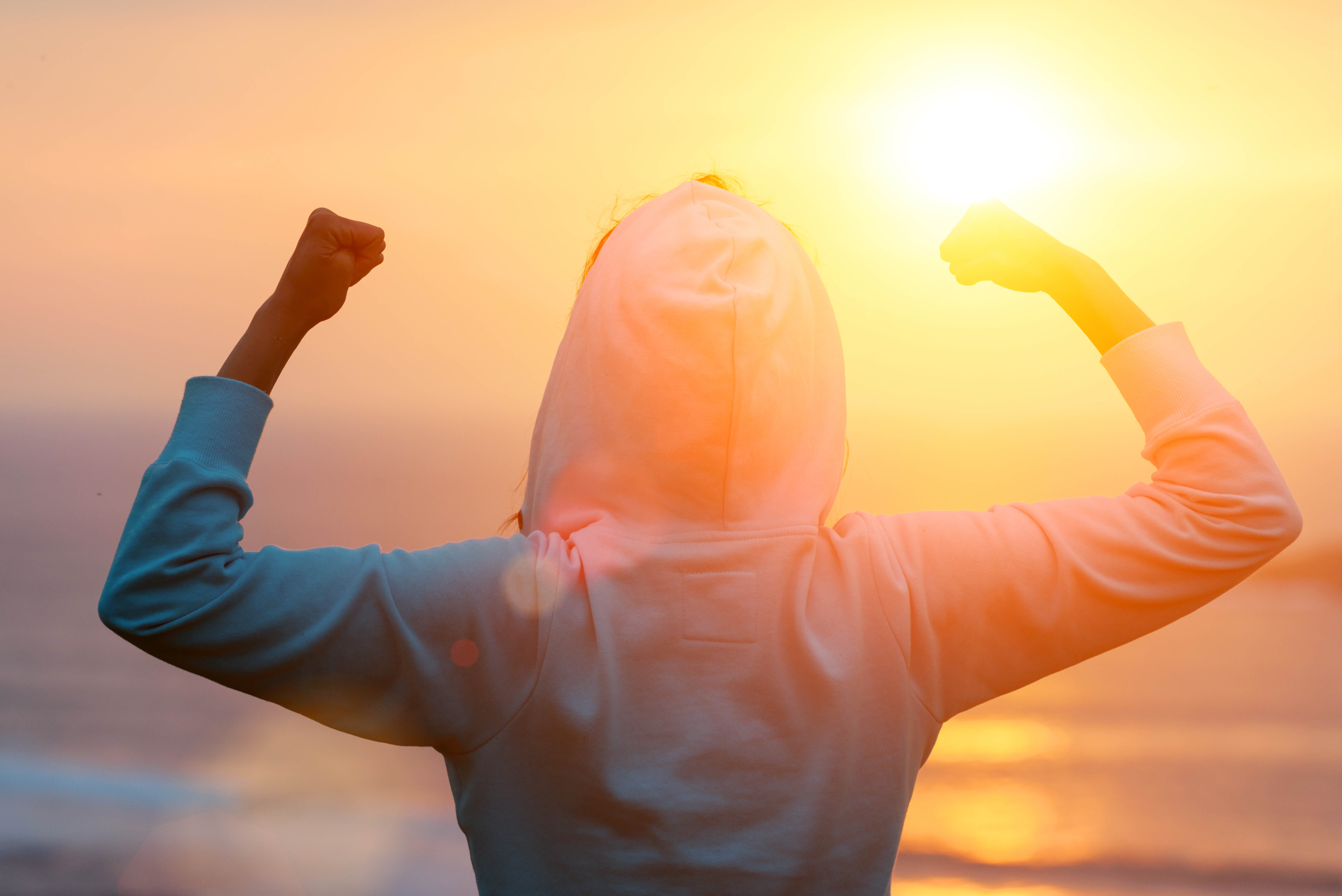 Back of a woman flexing facing the sunrise